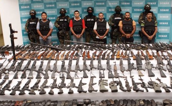 Police posing behind weapons seized from the Los Zetas. 